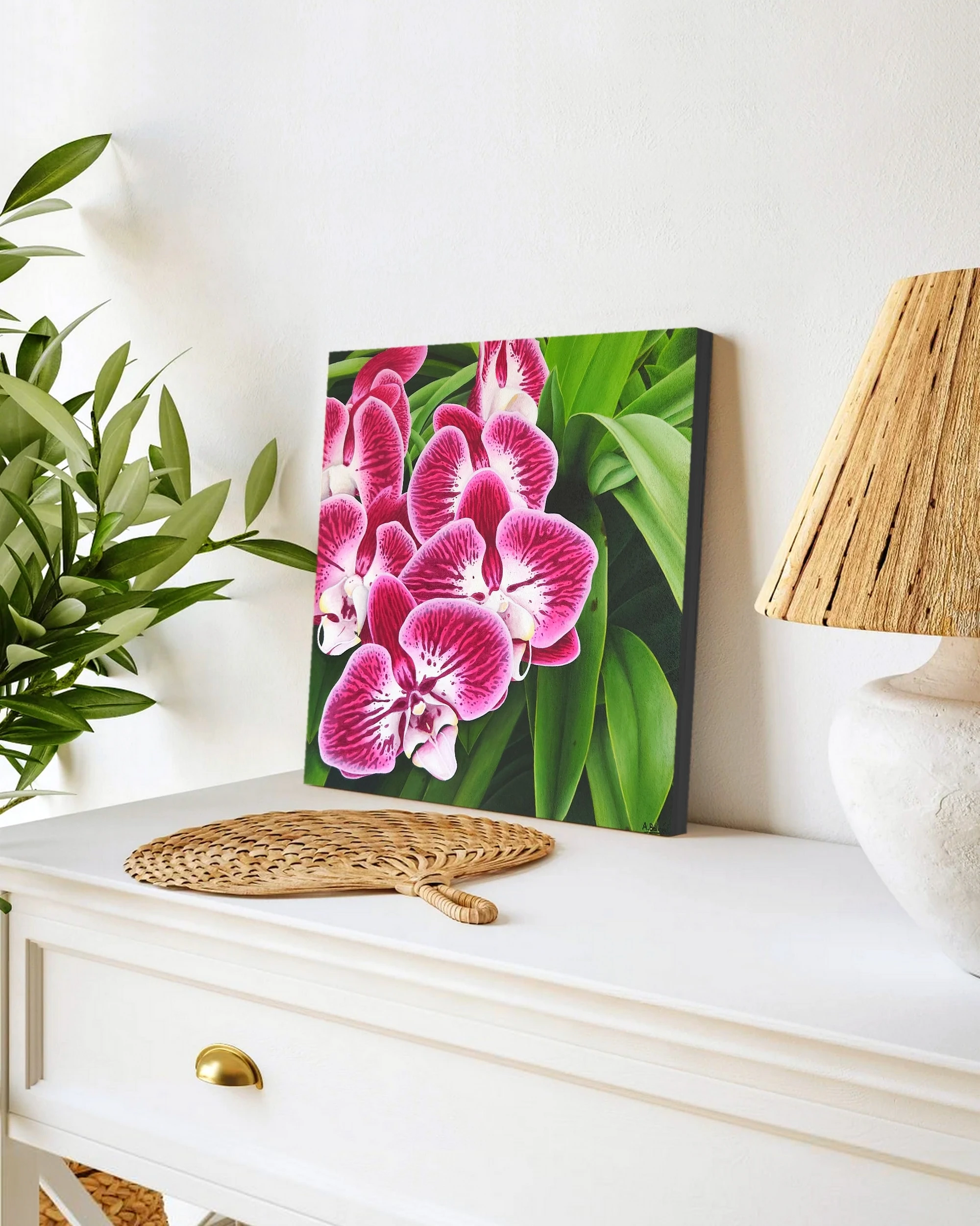 Tableau en peinture de fleurs d'orchidée roses avec son feuillage posée sur un meuble pour une décoration bord de mer tropical exotique