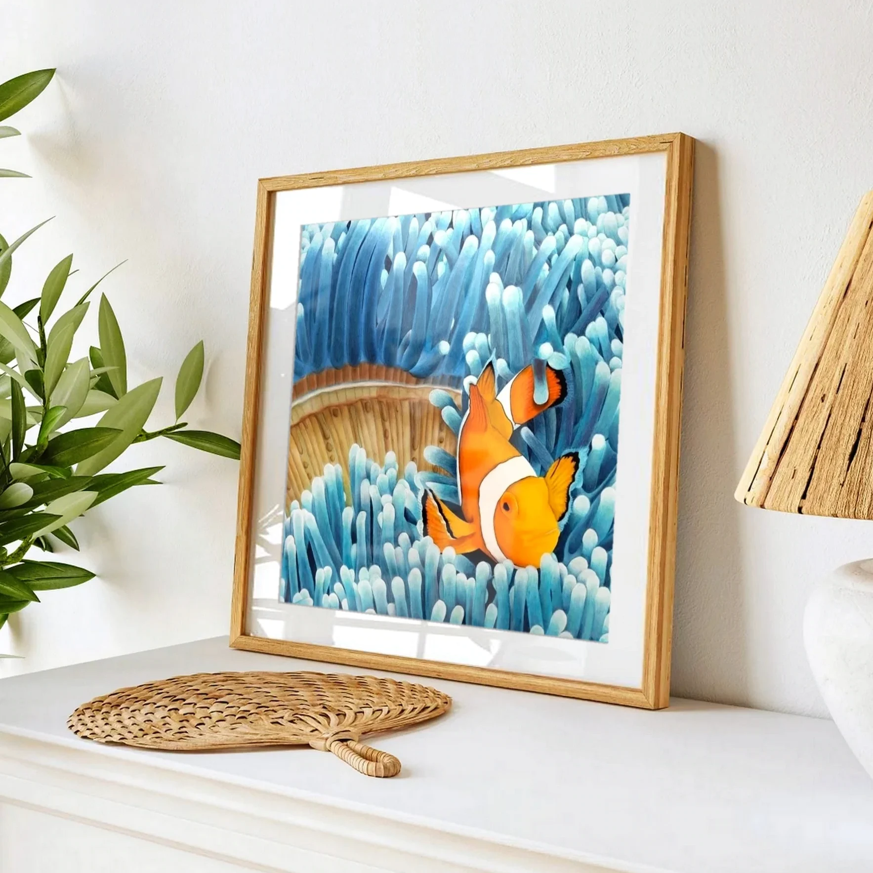 Affiche d'art d'une peinture de poisson clown dans les anémones bleues posée sur un meuble pour une décoration bord de mer exotique