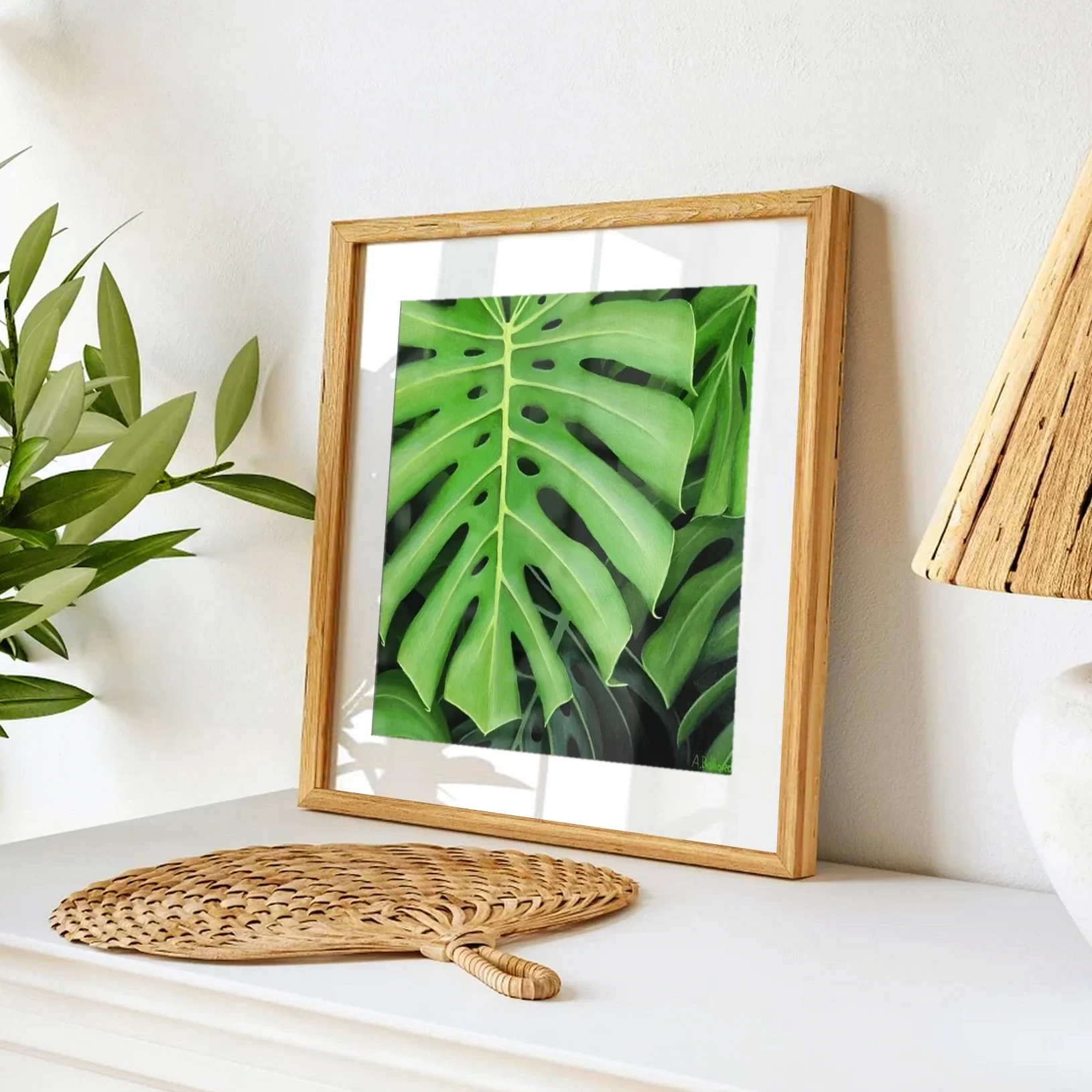 Affiche d'art d'une peinture d'un feuillage de plante monstera posée sur un meuble pour un style tropical exotique
