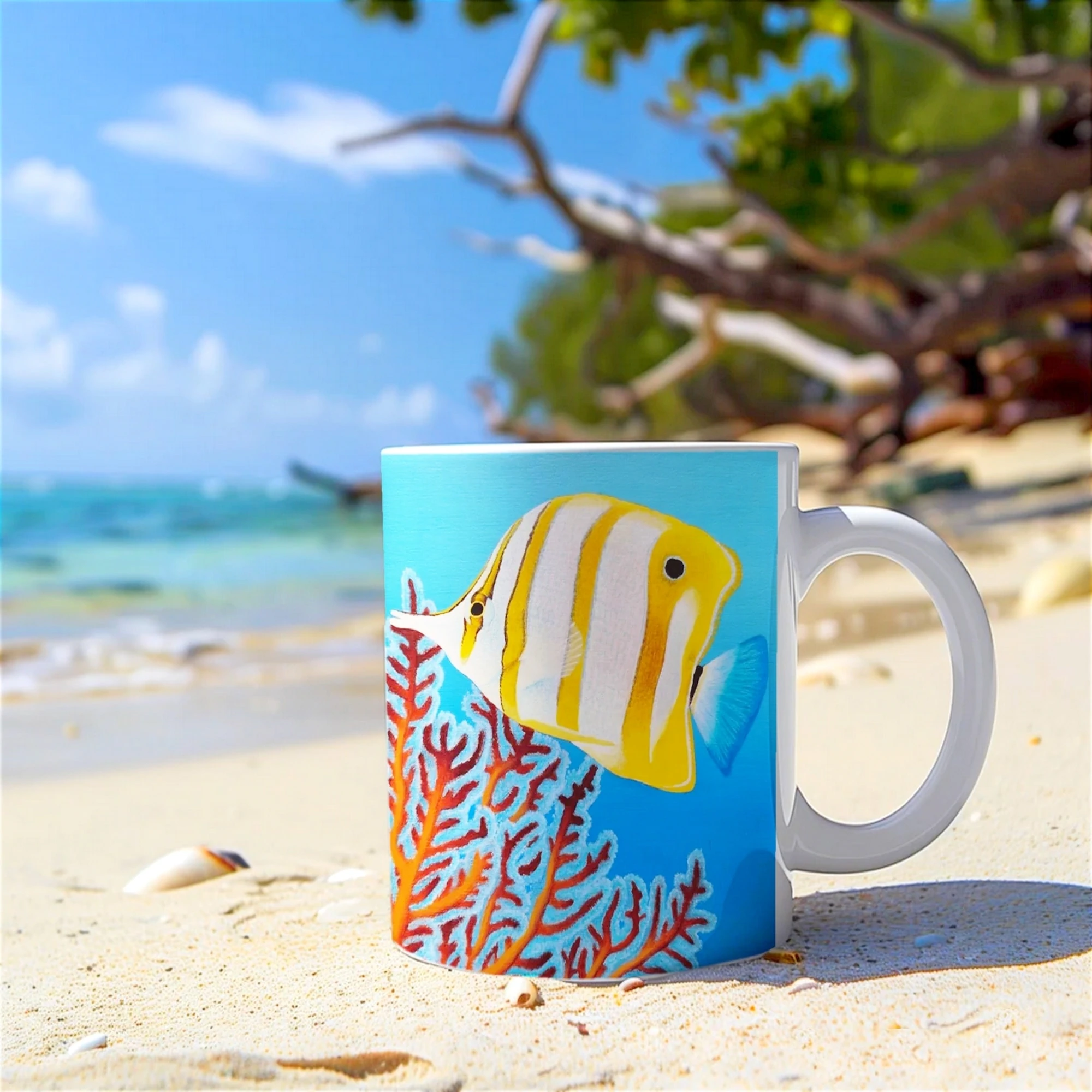 Mug artistique avec un poisson Chelmon, posé sur la plage avec l’océan en arrière-plan, un design inspiré de la vie marine.