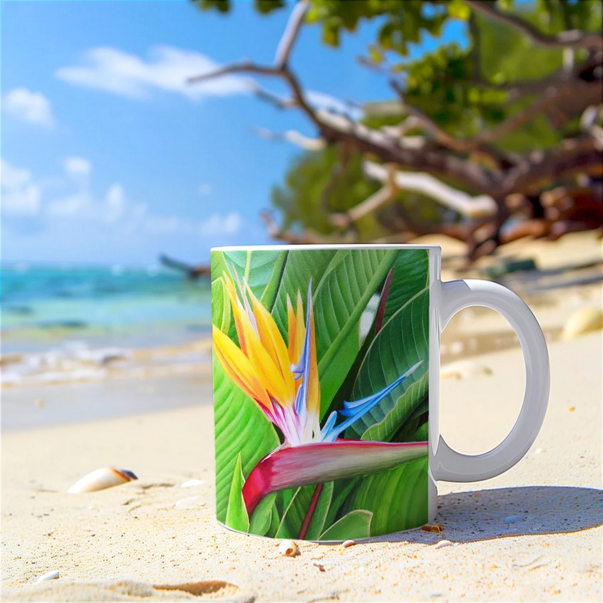 Mug avec fleur de Strelitzia posé sur la plage, vue sur l’océan, un design vibrant pour égayer vos pauses café en bord de mer.