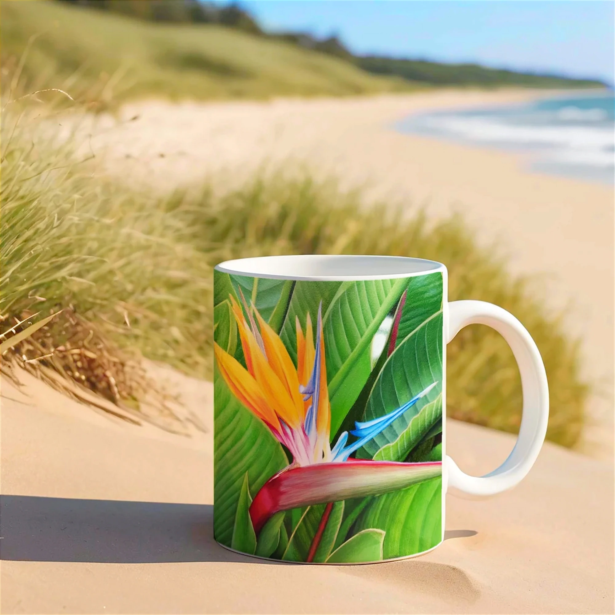 Mug avec fleur de Strelitzia posé sur le sable, une touche d’élégance tropicale sur la plage pour vos moments de détente.