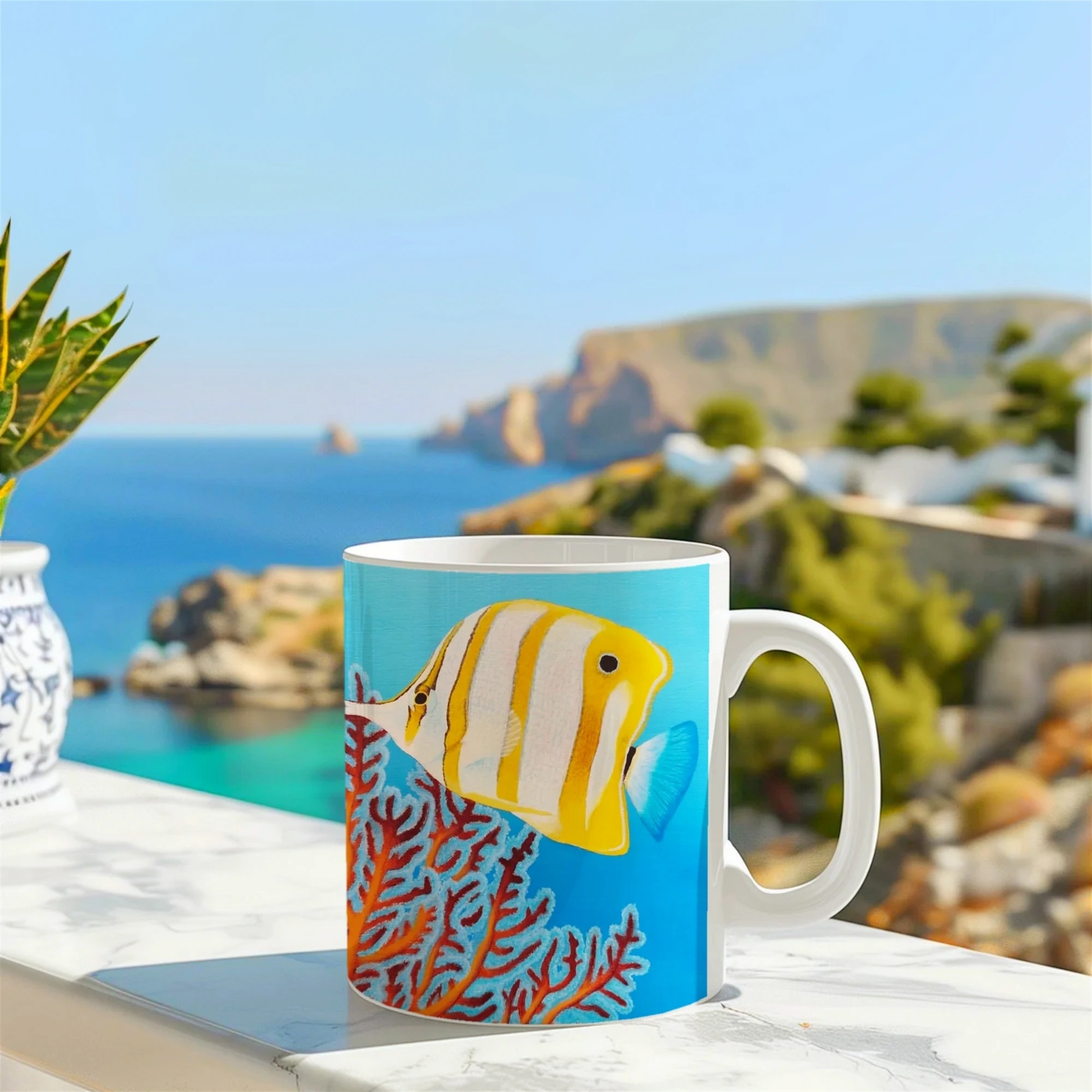 Mug décoré d'un poisson Chelmon dans les récifs, posé sur un muret devant la mer, pour les passionnés de la mer et du design marin.