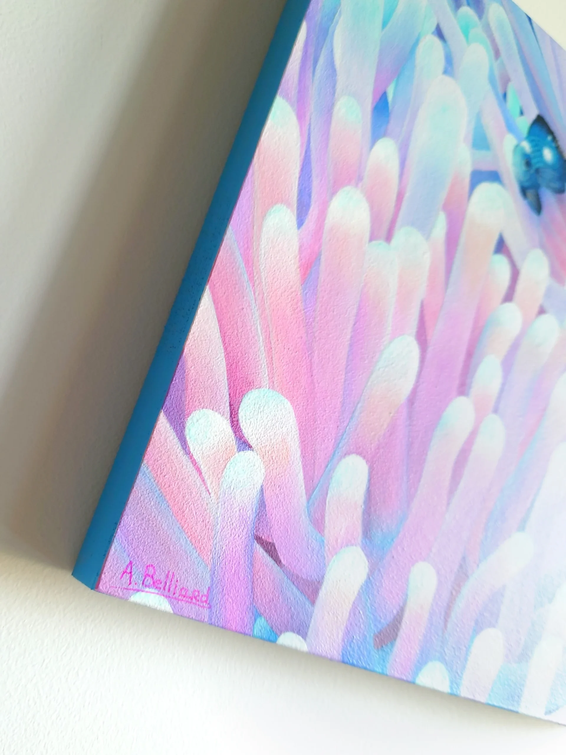 Peinture acrylique d'anémones de mer bleues et roses avec des petits poissons de taille 20x20 cm accroché sur un mur.