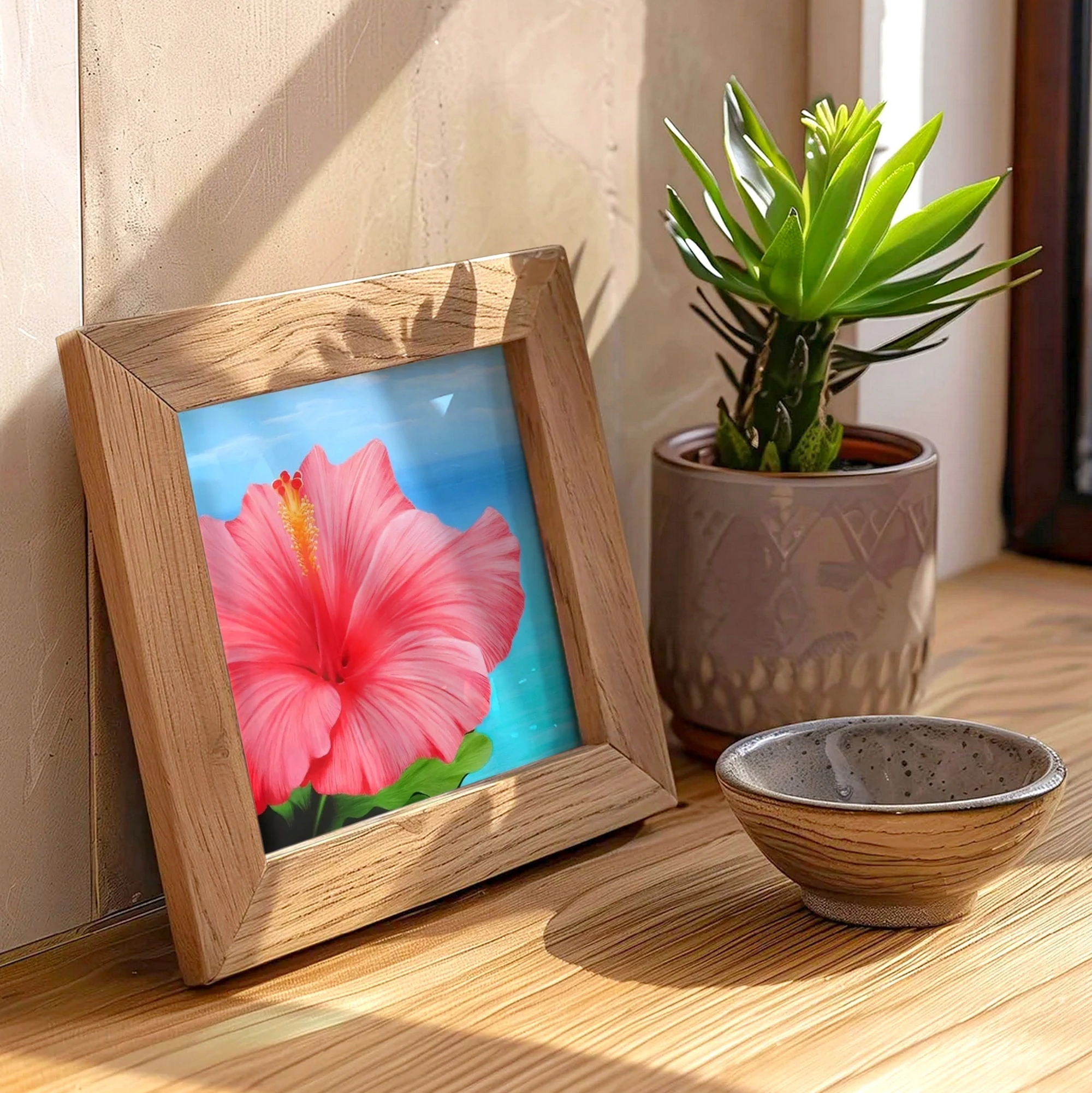 Poster d'art d'une peinture de fleur d'hibiscus rose devant l'océan posée sur un meuble pour une décoration bord de mer tropical exotique