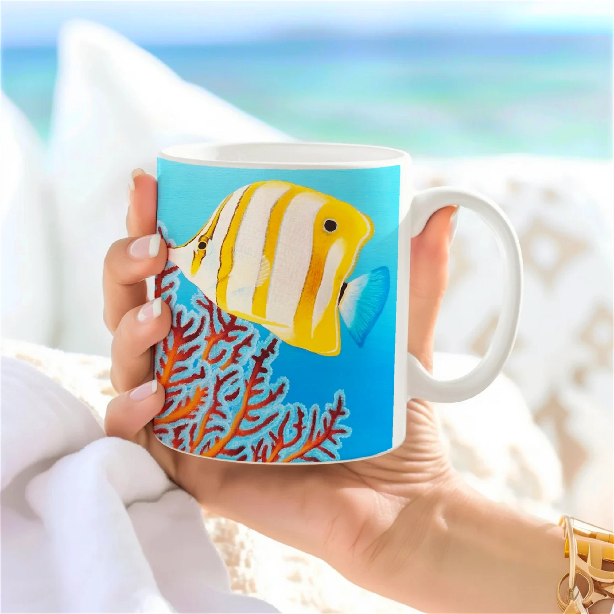 Tasse en céramique avec poisson Chelmon nageant parmi les récifs, vue latérale tenue dans une main, design océanique unique.